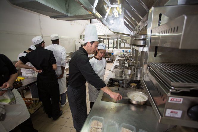 Elèves cuisiniers en apprentissage avec un professeur dans une cuisine