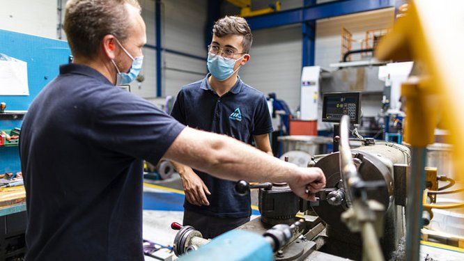 Deux salariés en interaction sur une machine dans une entreprise industrielle