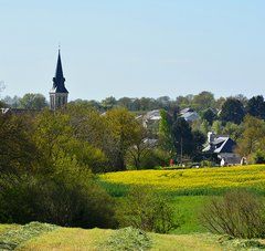 des champs et au loin un bourg avec un clocher et quelques habitations